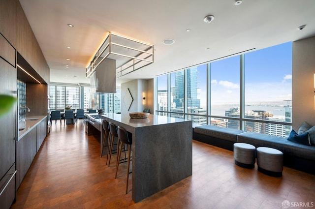 kitchen with expansive windows, dark hardwood / wood-style floors, a breakfast bar area, and a center island