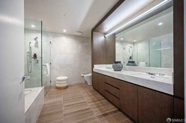 full bathroom with tile patterned flooring, vanity, tile walls, toilet, and separate shower and tub