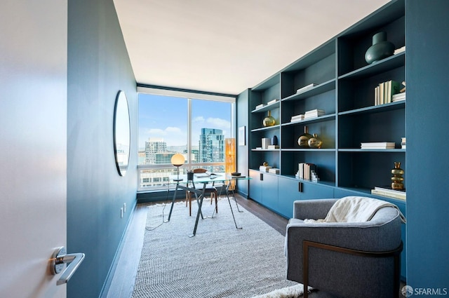 office space with built in shelves, a wall of windows, and hardwood / wood-style floors