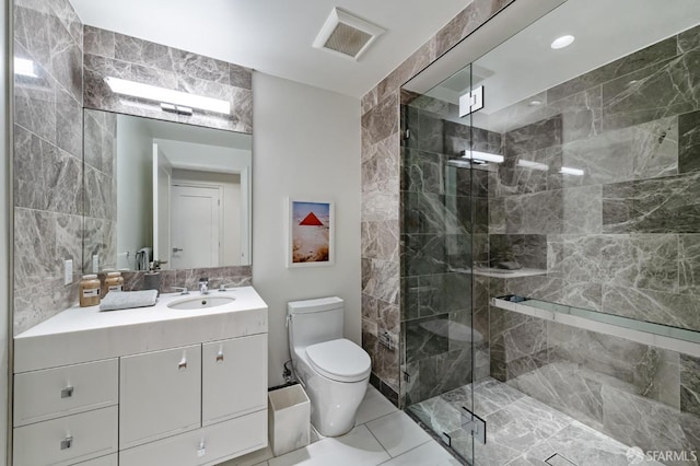 bathroom with tile patterned floors, vanity, tile walls, toilet, and a shower with shower door