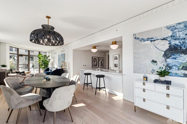 dining space with light wood-type flooring and crown molding