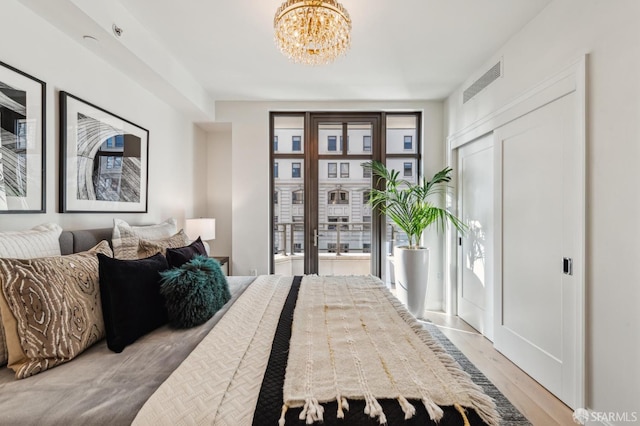 bedroom with multiple windows, light wood-type flooring, and an inviting chandelier