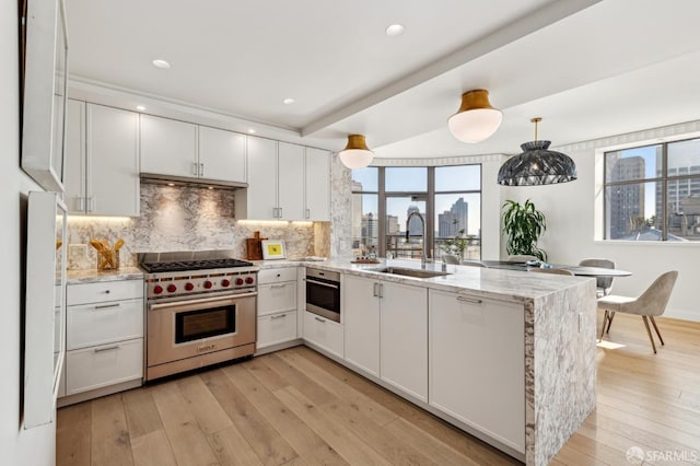 kitchen featuring kitchen peninsula, designer stove, white cabinetry, and light stone counters