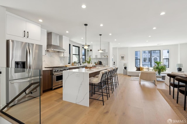 867 33rd Ave, San Francisco, CA 94121 - kitchen with wall chimney range hood, appliances with stainless steel finishes, a kitchen breakfast bar, a center island, and recessed lighting