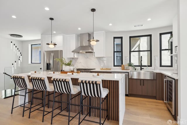 867 33rd Ave, San Francisco, CA 94121 - kitchen featuring wall chimney exhaust hood, appliances with stainless steel finishes, wine cooler, a sink, and a center island