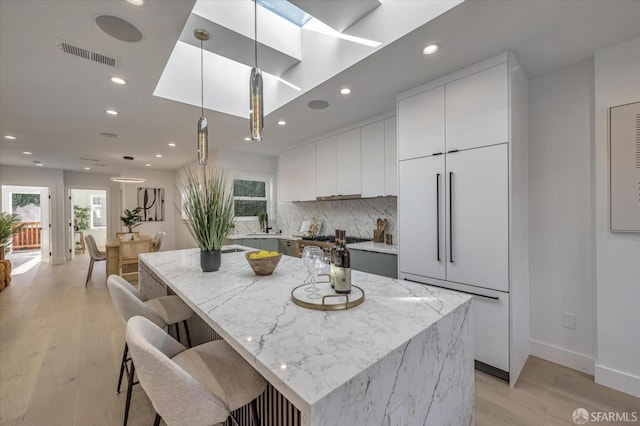 kitchen with light wood-type flooring, white cabinetry, pendant lighting, and a center island