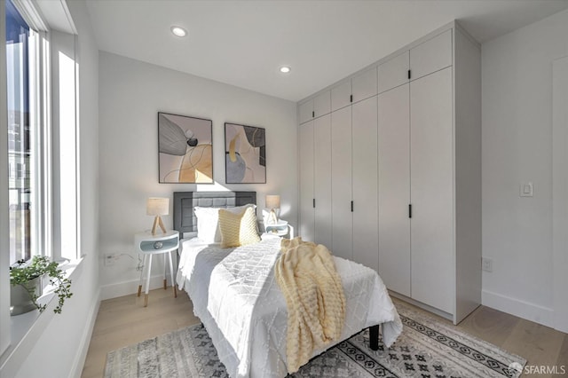 bedroom featuring a closet, multiple windows, and light hardwood / wood-style floors