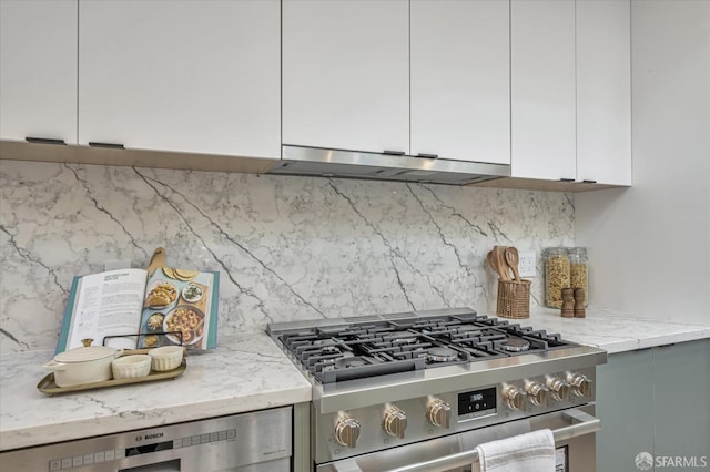 kitchen with tasteful backsplash, light stone countertops, gray cabinets, and stainless steel stove