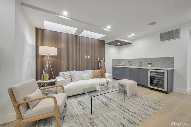 living room featuring indoor wet bar, beverage cooler, and light hardwood / wood-style flooring