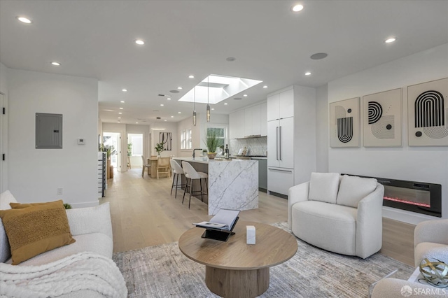 living room featuring light hardwood / wood-style floors, electric panel, and a skylight