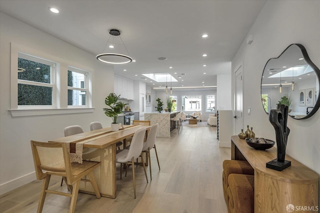 dining area with light wood-type flooring and a skylight