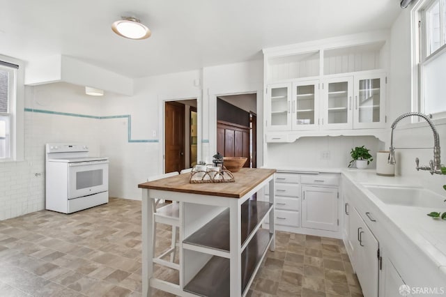 kitchen with wooden counters, stone finish flooring, white cabinets, a sink, and white electric stove