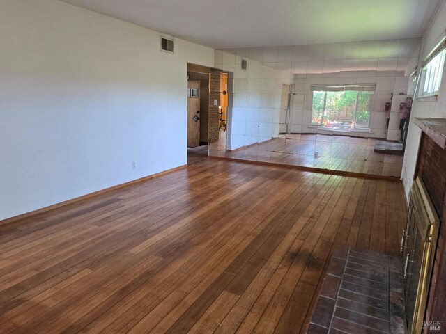 unfurnished living room with wood-type flooring and visible vents
