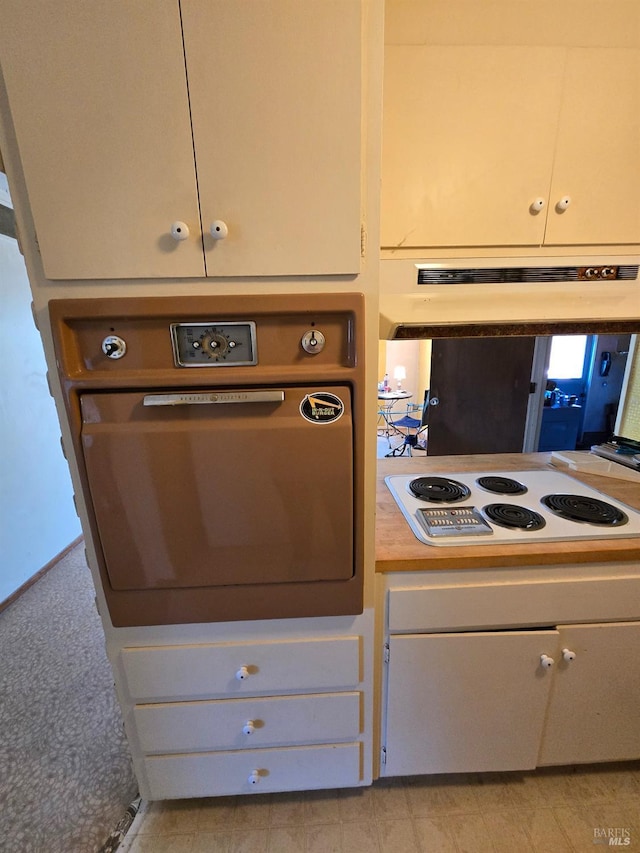 kitchen featuring white electric stovetop, white cabinetry, under cabinet range hood, and oven