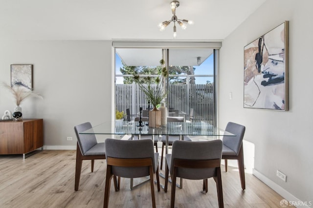 dining area with light hardwood / wood-style floors, floor to ceiling windows, and a chandelier