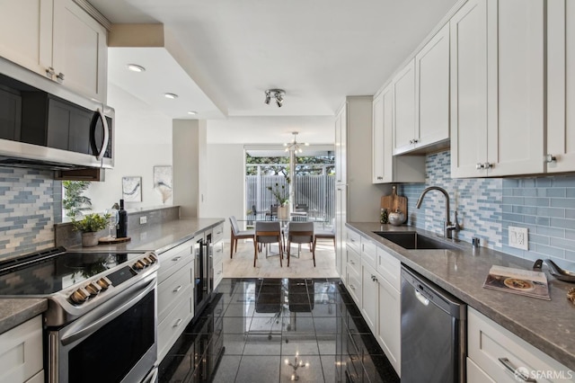 kitchen featuring sink, tasteful backsplash, appliances with stainless steel finishes, dark stone counters, and white cabinets