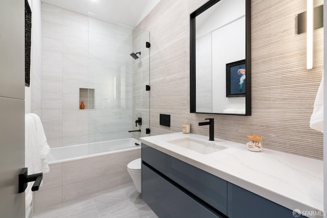 full bathroom featuring toilet, tiled shower / bath, tile walls, vanity, and tile patterned flooring