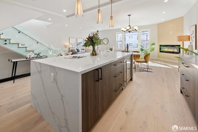 2219 Bryant St, San Francisco, CA 94110 - kitchen featuring light hardwood / wood-style floors, a large island, decorative light fixtures, dark brown cabinetry, and light stone counters
