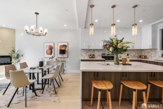 kitchen featuring pendant lighting, backsplash, white cabinetry, electric stove, and light hardwood / wood-style floors