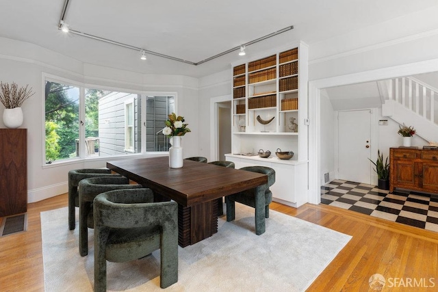 dining room with stairs, light wood-style flooring, visible vents, and track lighting