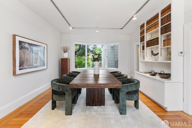 dining space with light wood-style flooring, baseboards, and track lighting