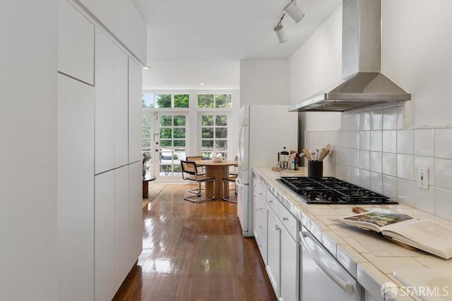 kitchen featuring tile counters, white cabinets, decorative backsplash, and ventilation hood