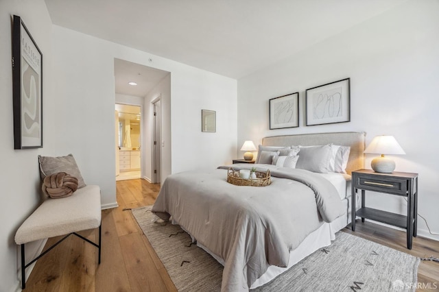 bedroom with light hardwood / wood-style flooring and ensuite bath