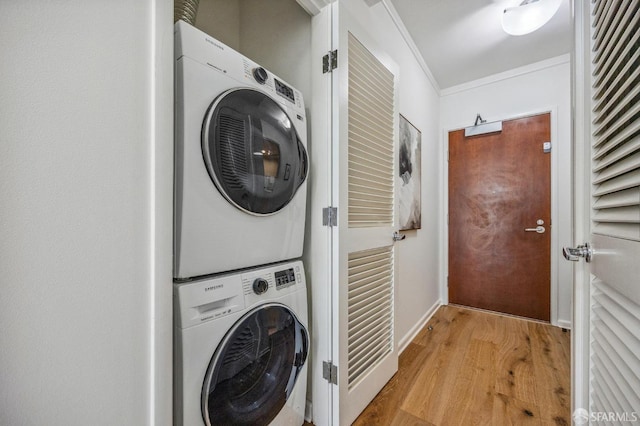 laundry area featuring stacked washer and clothes dryer, crown molding, and light hardwood / wood-style floors