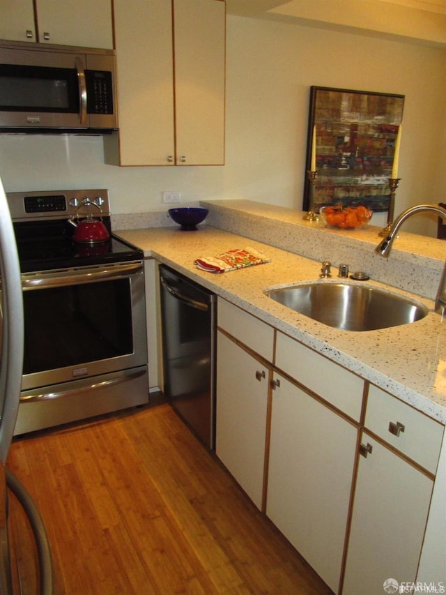 601 Van Ness Ave Unit 1102, San Francisco, CA 94102 - kitchen featuring appliances with stainless steel finishes, wood finished floors, light stone countertops, and white cabinetry