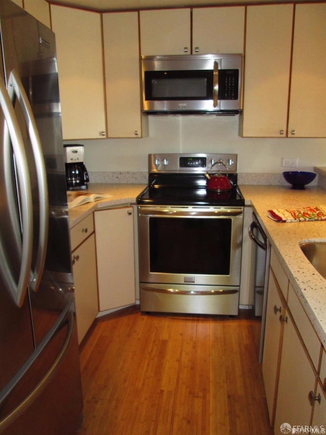601 Van Ness Ave Unit 1102, San Francisco, CA 94102 - kitchen with stainless steel appliances, light wood-style floors, and cream cabinets