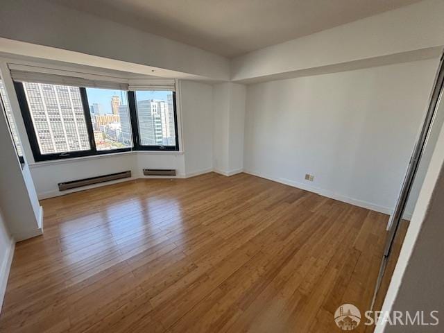 601 Van Ness Ave Unit 1102, San Francisco, CA 94102 - empty room featuring a baseboard heating unit, wood finished floors, and a baseboard radiator