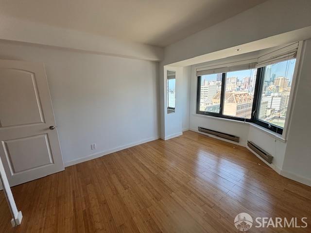 601 Van Ness Ave Unit 1102, San Francisco, CA 94102 - unfurnished room with a baseboard heating unit and wood finished floors