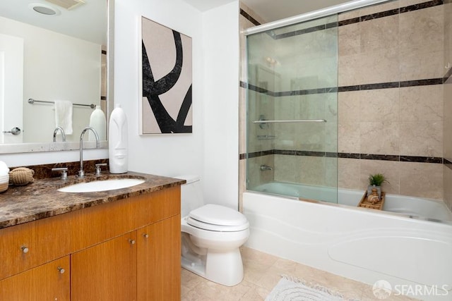 full bathroom with combined bath / shower with glass door, tile patterned floors, toilet, and vanity