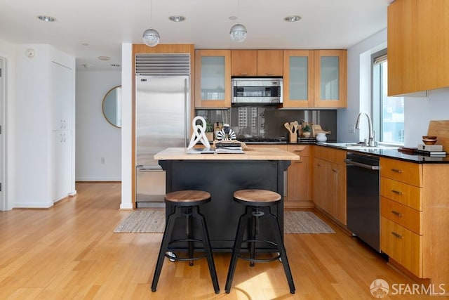 kitchen featuring a kitchen island, pendant lighting, light hardwood / wood-style floors, and stainless steel appliances