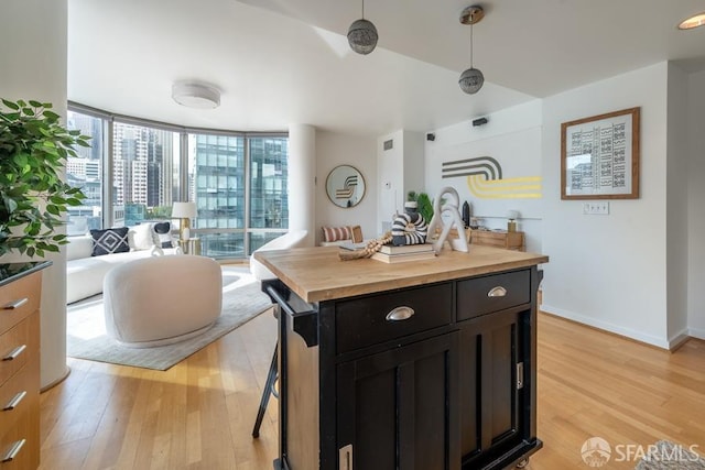 kitchen featuring butcher block counters, floor to ceiling windows, light wood-type flooring, and a kitchen island