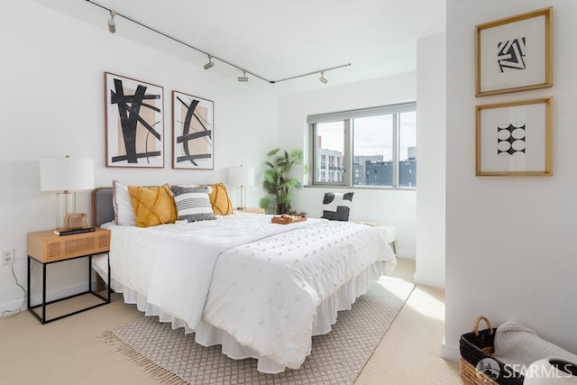 bedroom featuring light carpet and rail lighting