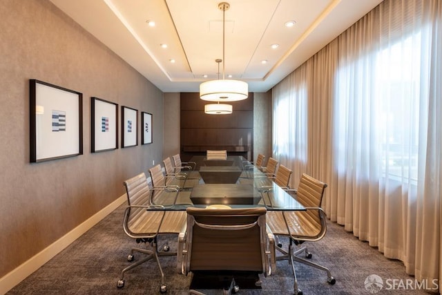 carpeted dining space with a raised ceiling