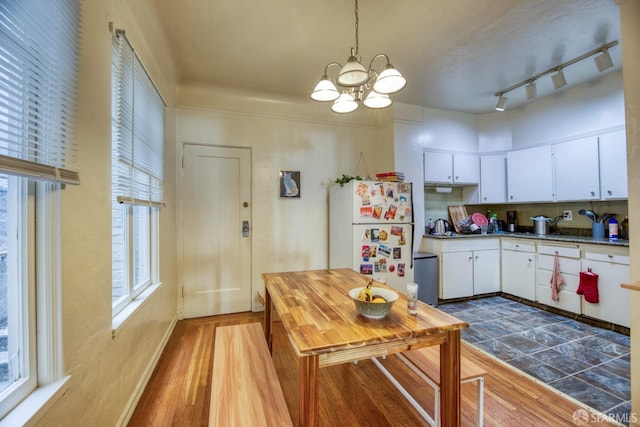 kitchen with white refrigerator, tasteful backsplash, white cabinets, and decorative light fixtures