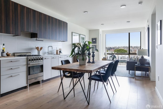 kitchen with high end stainless steel range oven, white cabinetry, dark brown cabinets, and a healthy amount of sunlight