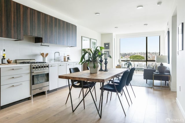 kitchen featuring dark brown cabinetry, white cabinetry, tasteful backsplash, light hardwood / wood-style flooring, and high end stove