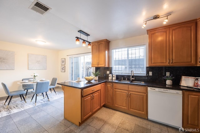 kitchen featuring visible vents, backsplash, dishwasher, a peninsula, and a sink