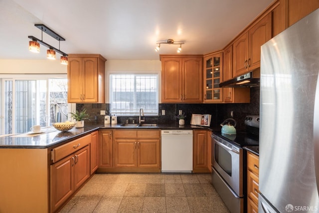 kitchen featuring under cabinet range hood, a peninsula, granite finish floor, stainless steel appliances, and a sink