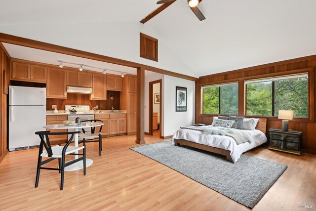 bedroom featuring a sink, beam ceiling, high vaulted ceiling, light wood-style flooring, and freestanding refrigerator