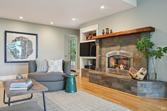 living room featuring recessed lighting, baseboards, wood finished floors, and a fireplace