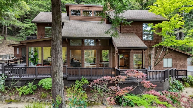 rear view of property with a deck and roof with shingles
