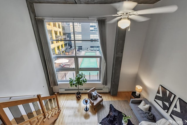 living room with a wealth of natural light, a baseboard radiator, light hardwood / wood-style flooring, and ceiling fan