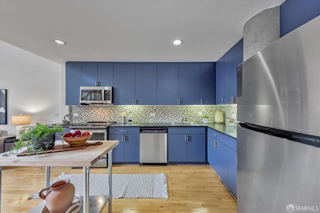 kitchen with appliances with stainless steel finishes, light hardwood / wood-style floors, and blue cabinets