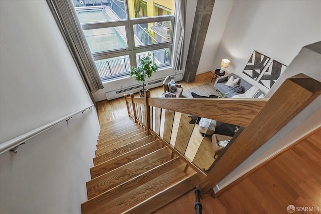 stairs featuring hardwood / wood-style flooring and a baseboard radiator