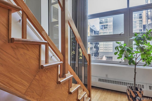 stairs featuring radiator heating unit and hardwood / wood-style flooring