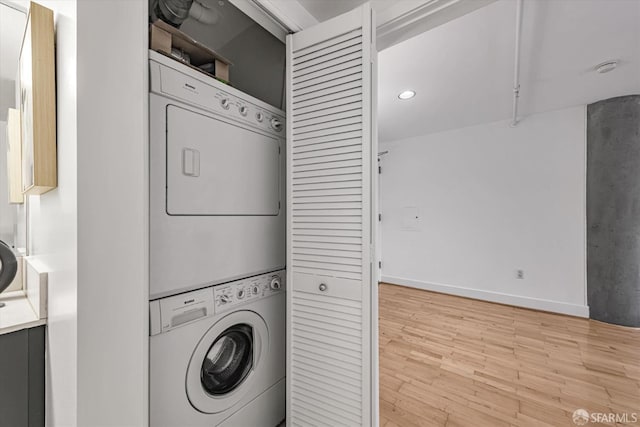 laundry area with stacked washing maching and dryer and light hardwood / wood-style floors